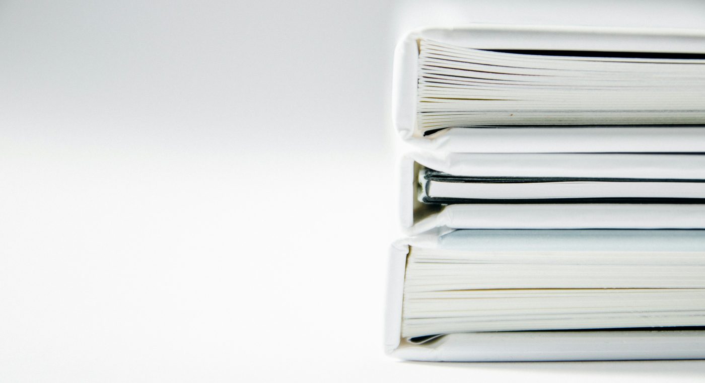 Una pila de archivadores blancos de anillas sobre una mesa blanca. Foto: Beatriz Pérez Moya en Unsplash.
