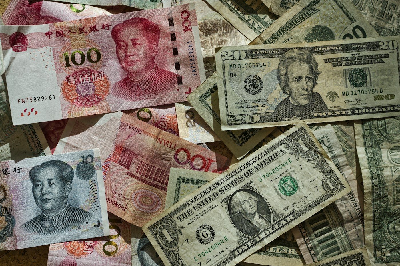 Billetes de yuan chinos y de dólar estadounidense mezclados sobre una mesa.