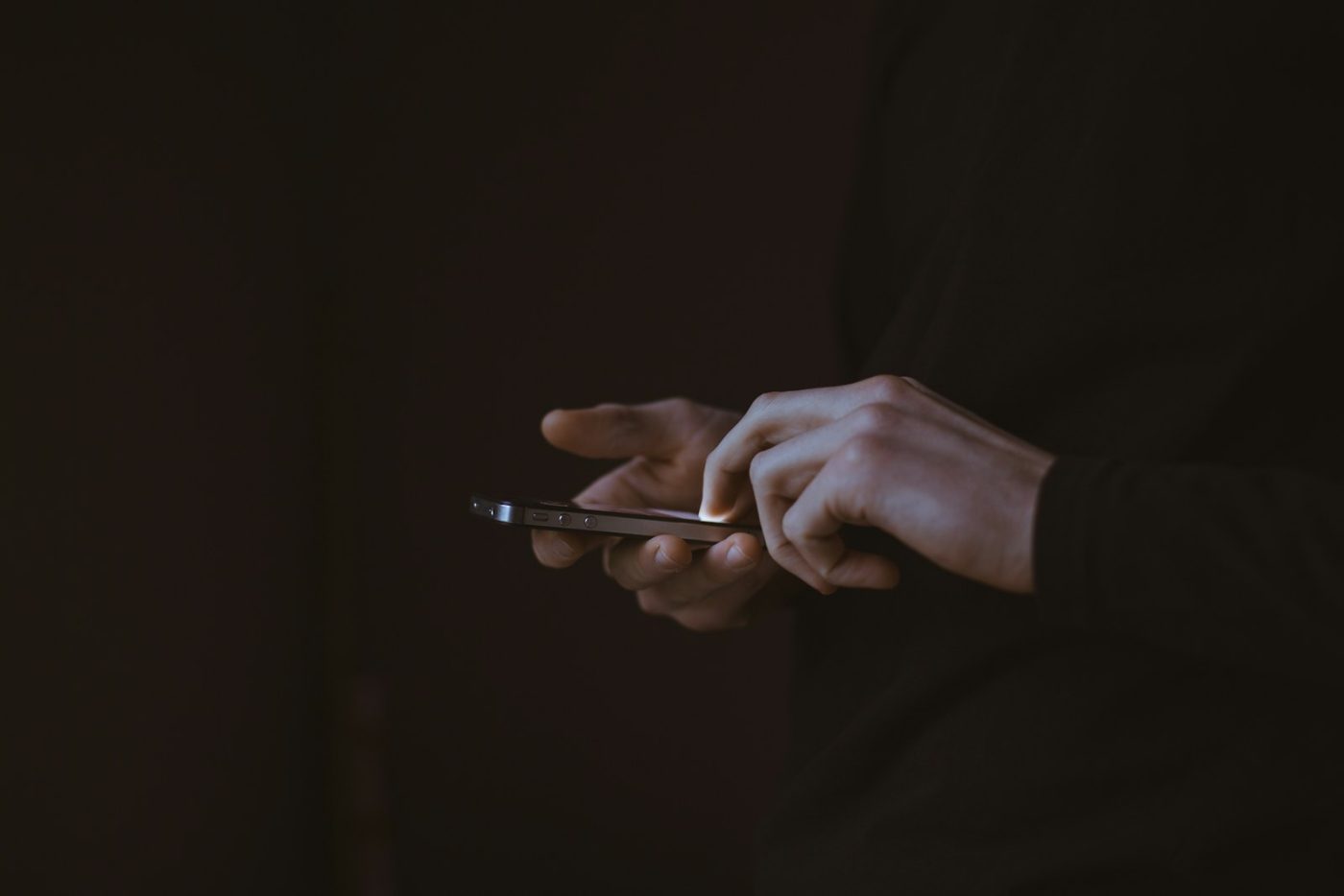 Una persona escribiendo en el móvil a oscuras. Foto: Gilles Lambert en Unsplash.