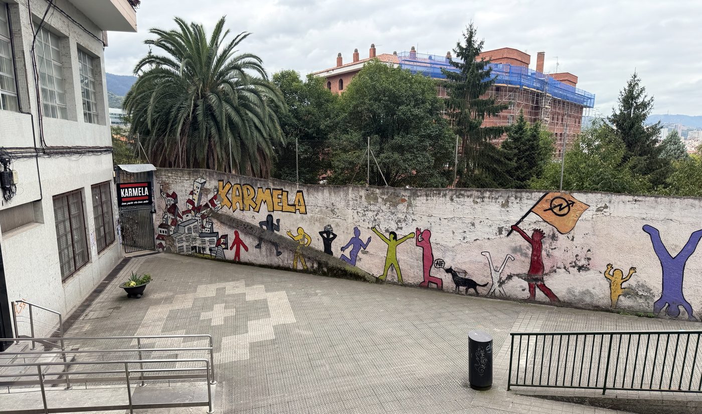 El patio de entrada a Karmela, en la calle Fika de Santutxu, con su mural y el cartel de la puerta.