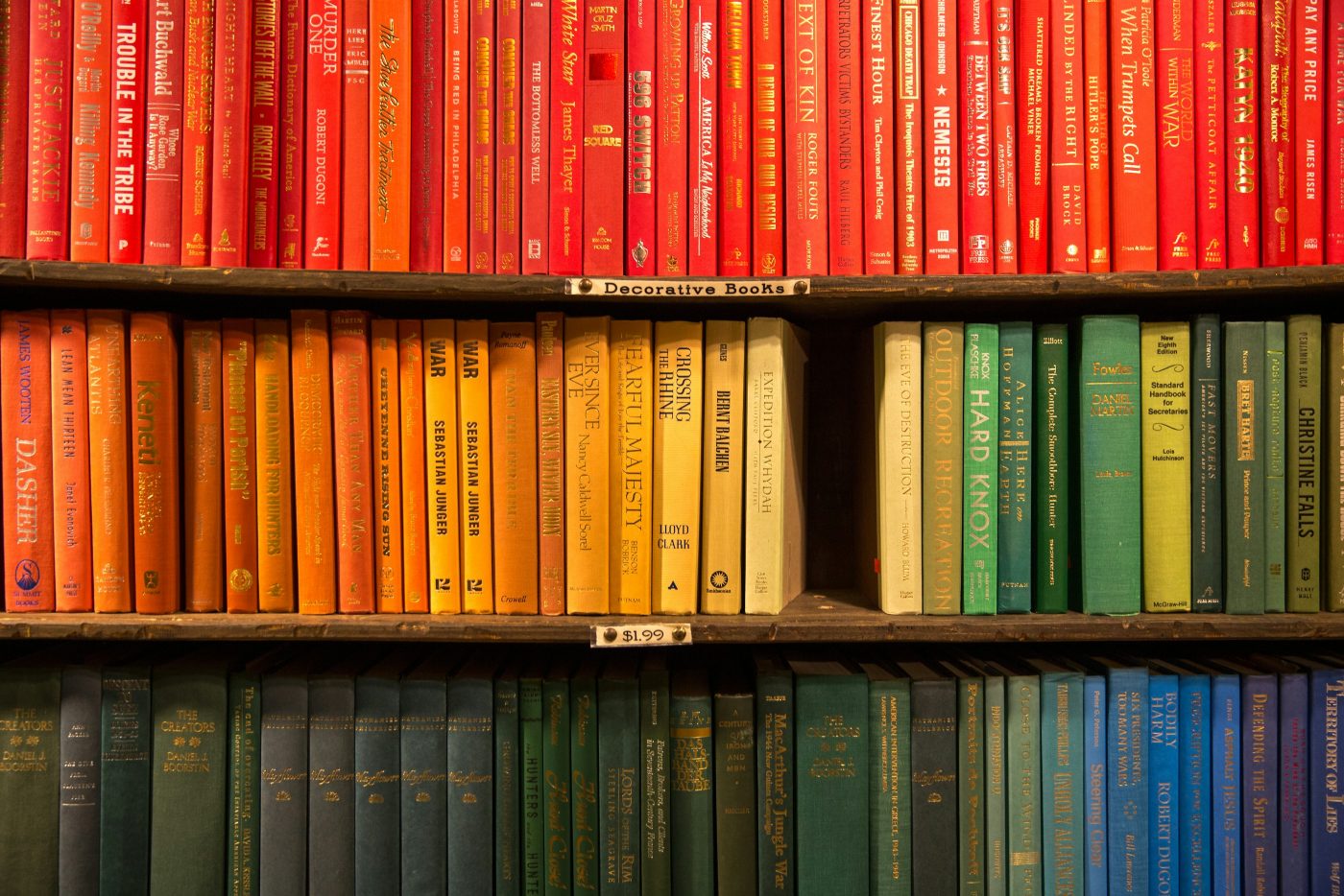 Estantería de una librería con libros de tapa dura ordenados por colores, del rojo al azul. El cartel de la balda dice «Decorative Books», libros para decorar, a 1,99 dólares. Foto: Jason Leung en Unsplash.