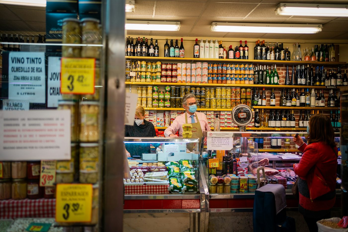 Un tendero atiende tras el mostrador de una tienda de ultramarinos, con las estanterías llenas de conservas y de vinos. Foto: Victoriano Izquierdo en Unsplash.